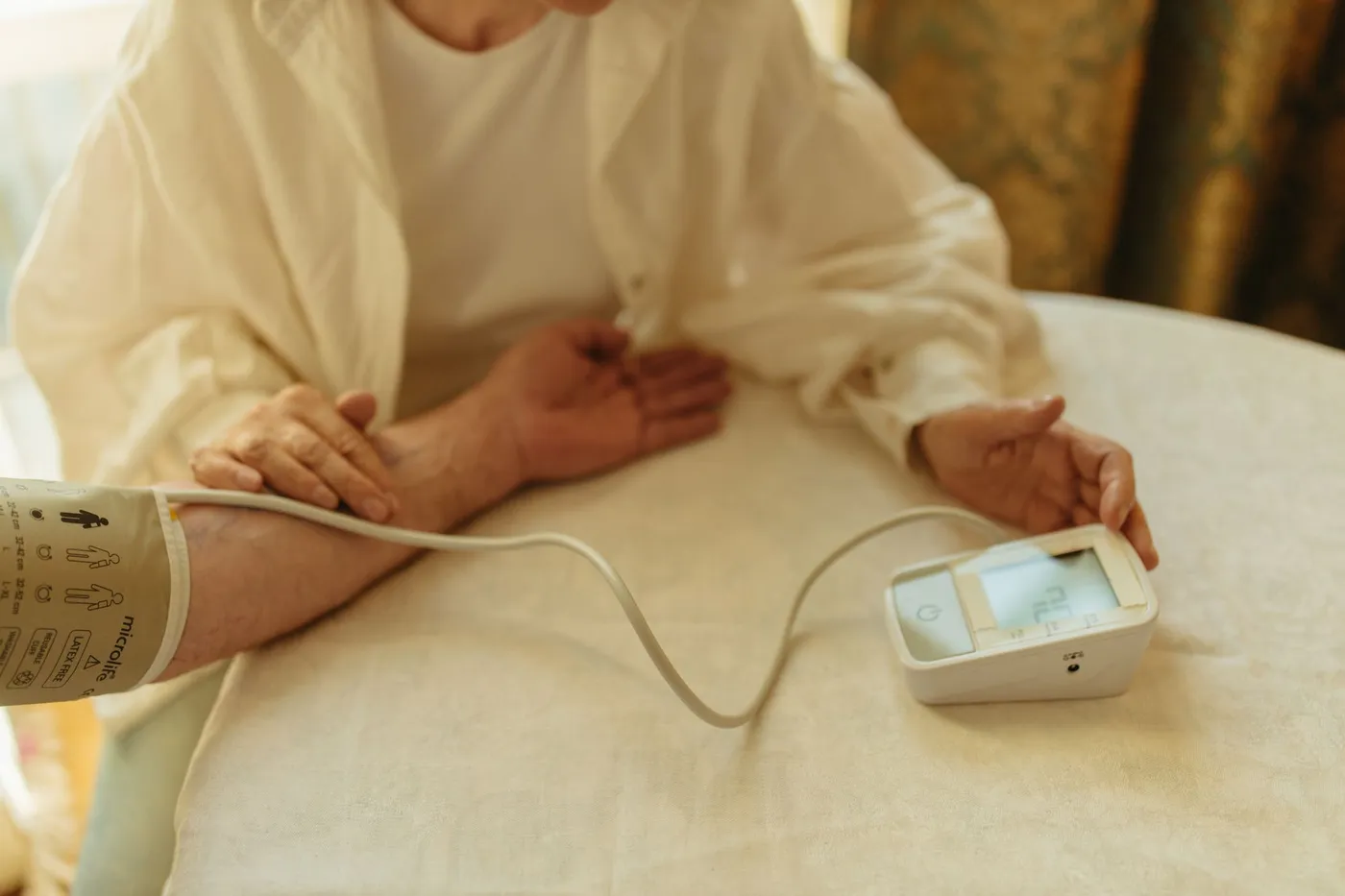 Arm with an upper-arm cuff resting relaxed on the table, the digital monitor next to it