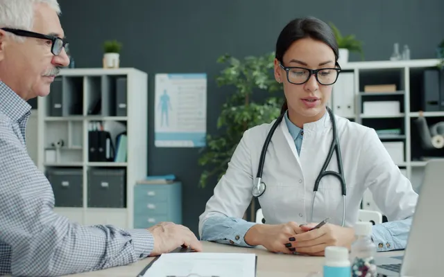 Doente idoso a conversar com uma médica no consultório