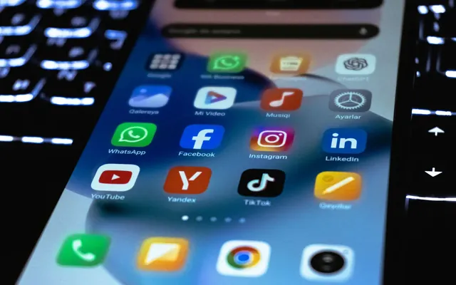 Hand hält ein Smartphone mit zahlreichen App-Symbolen